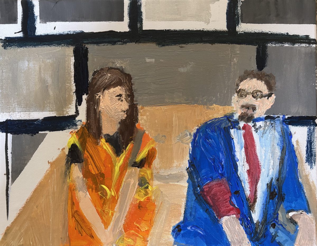 Broken by Superbed (Sam and Ellie) - Two seated before the panel — orange dress, blue suit, red tie.